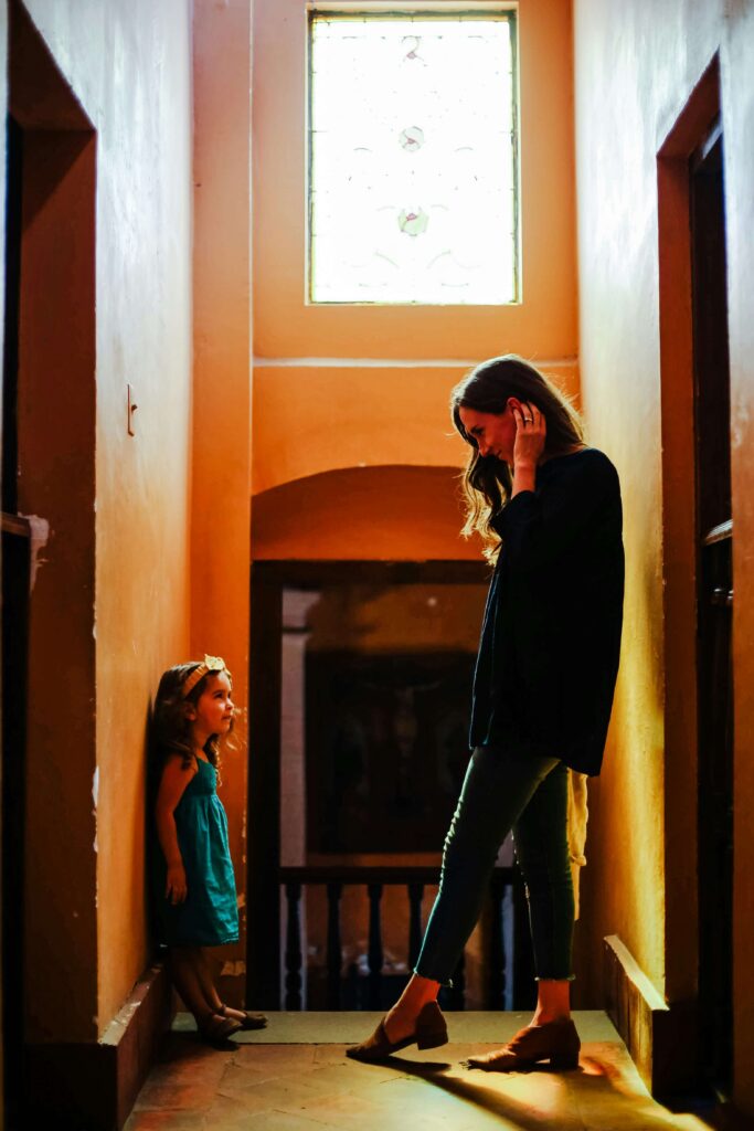 A child and woman together, in deep conversation in a hallway.
