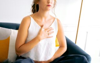 A woman with hand on her chest and stomach, who may be practicing somatic therapy